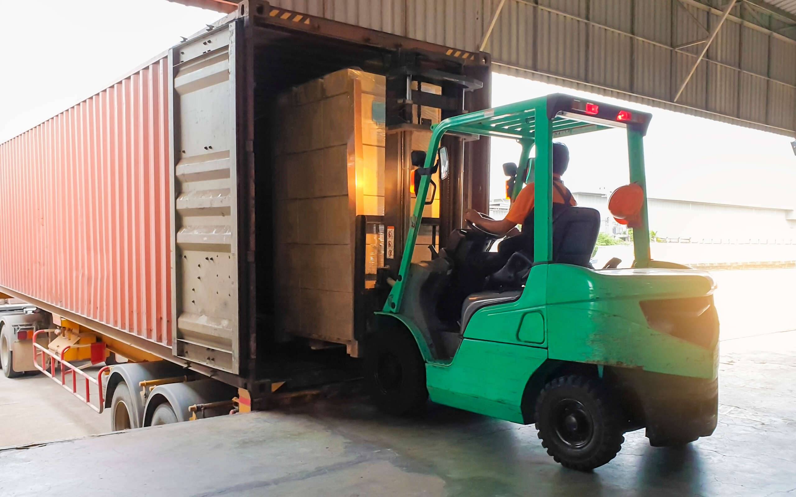 Forklift,Tractor,Loading,Package,Boxes,Into,Shipping,Container,At,Dock